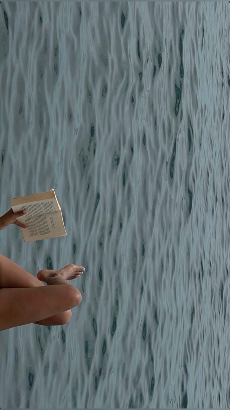 Legs and a book against a rippling water background